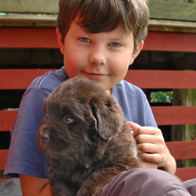 Liten pojke med en hundvalp i famnen